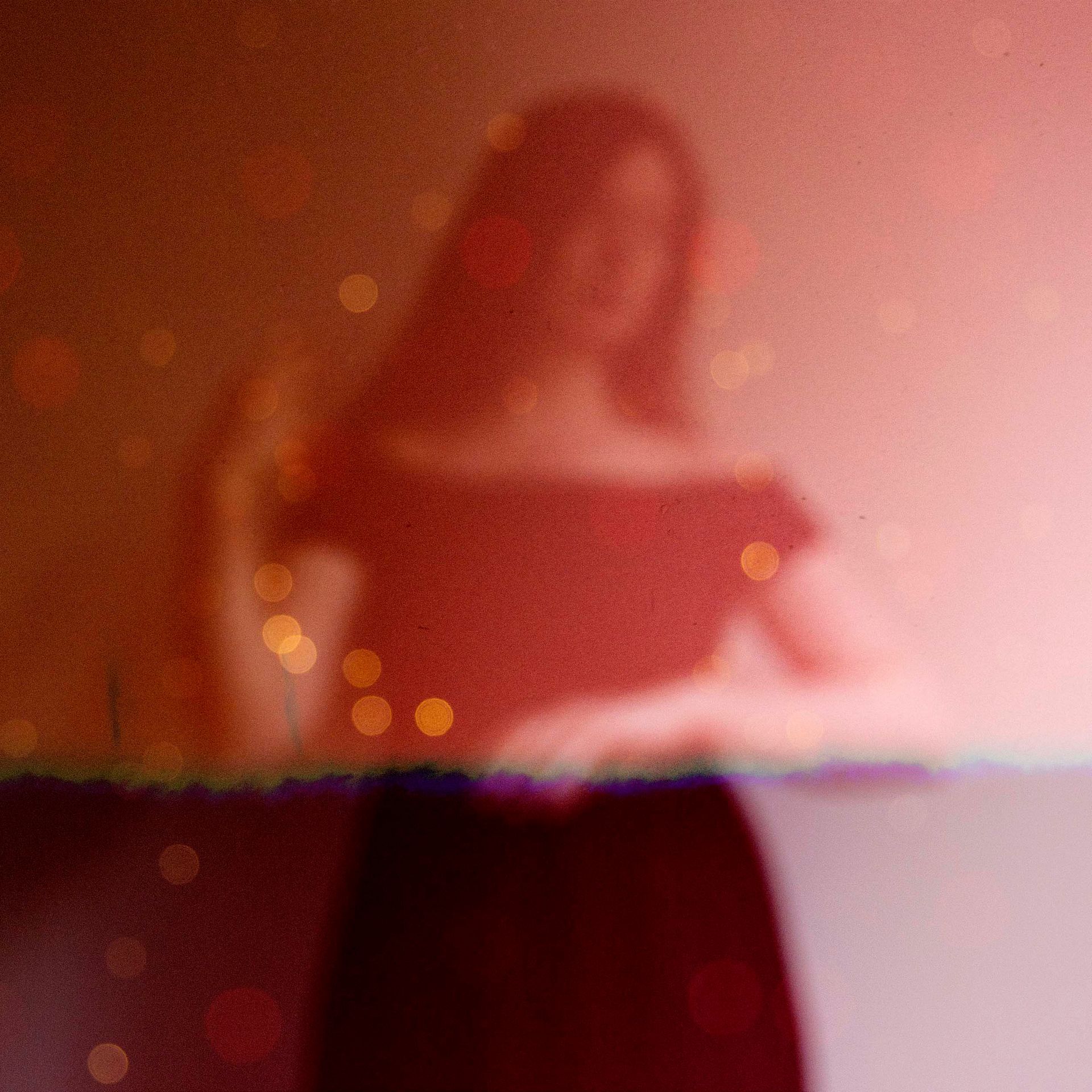 A blurry picture of a woman standing in front of a red wall.