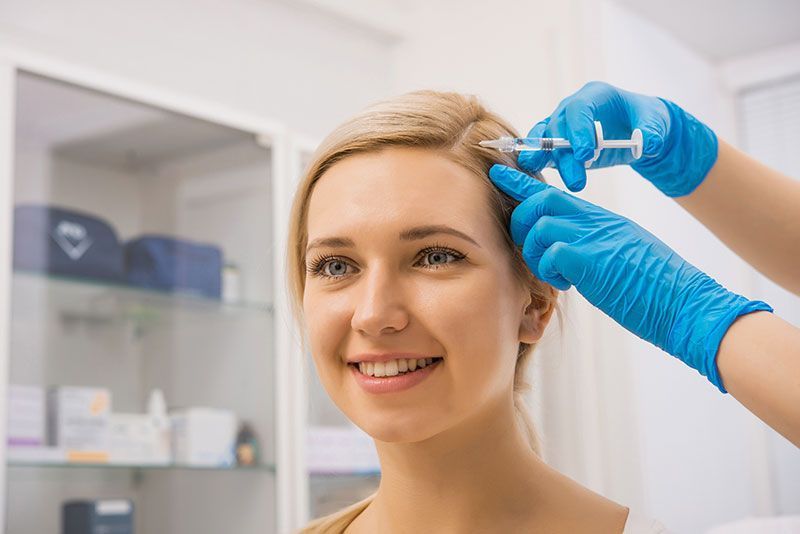 Woman receiving body contouring treatment with a handheld device on her thigh.