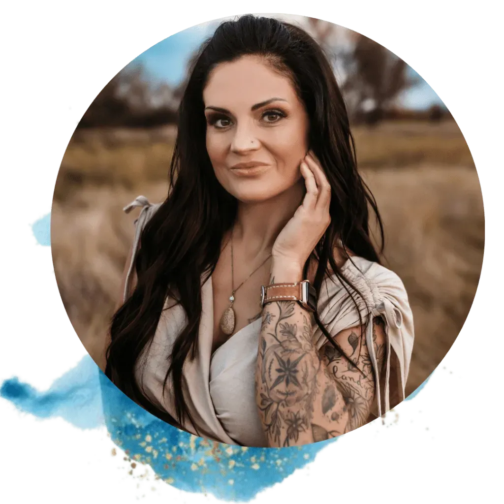 Woman with dark hair and arm tattoo, outdoors, smiling, hand on cheek, watch on wrist, in a field.