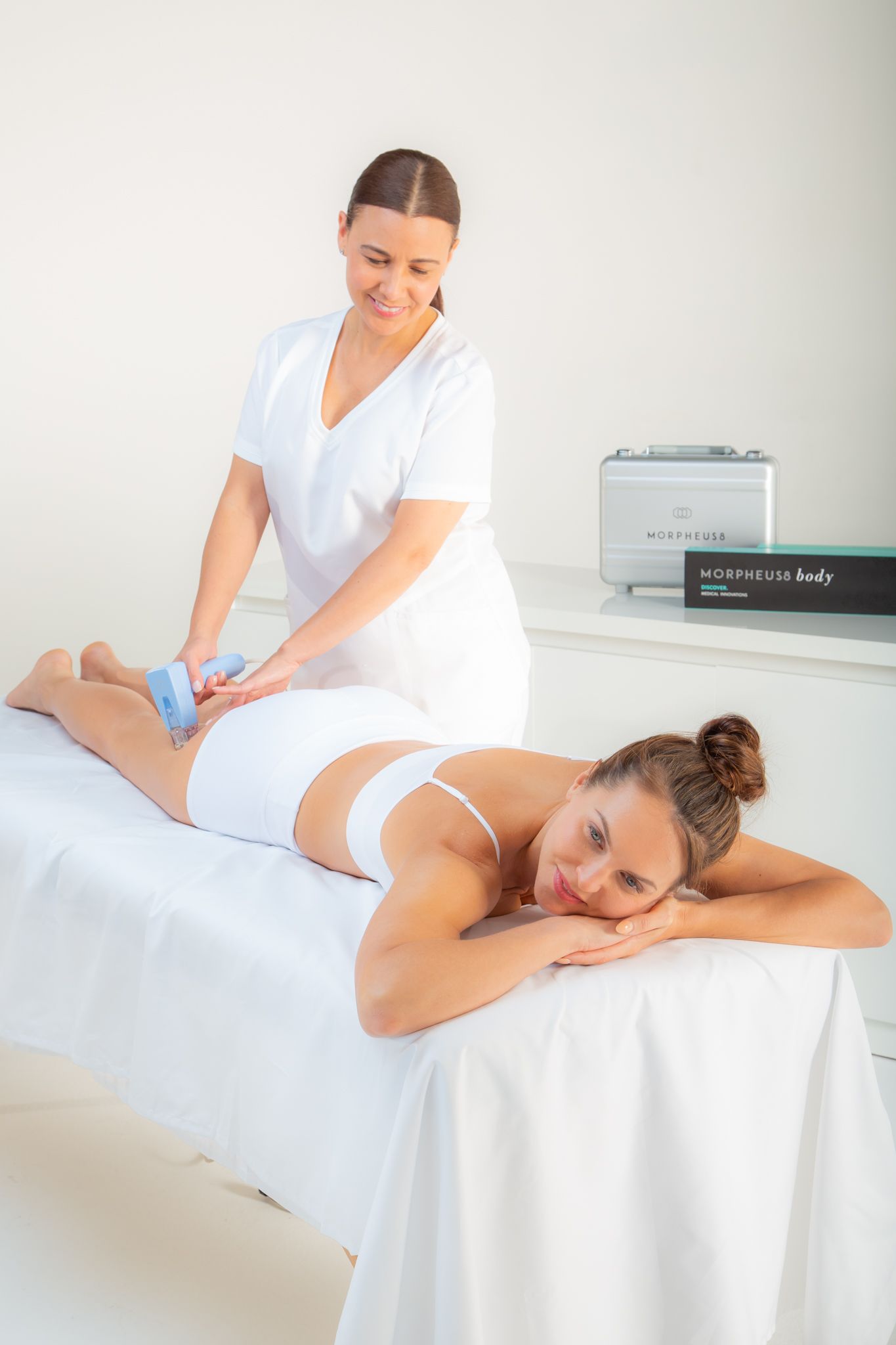 Person receiving body treatment in a clinic; a medical device is applied to the body.