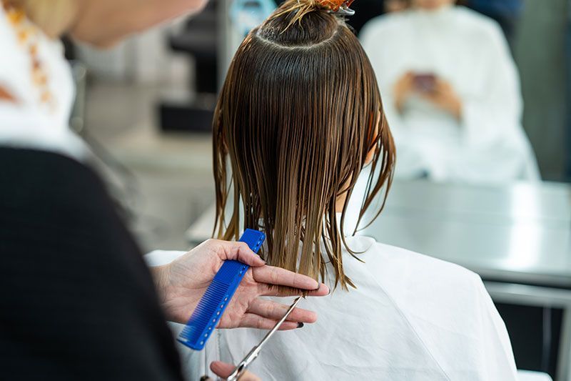 Hairdresser applying hair dye with a brush, using foil on a client's hair in a salon.