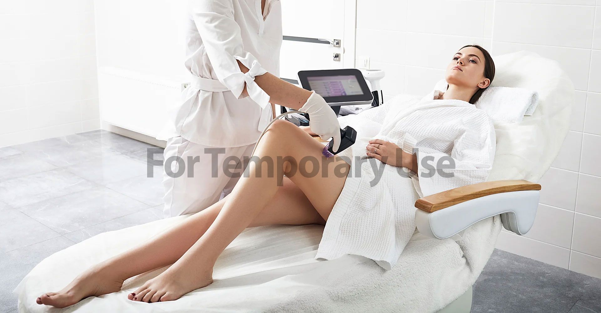 Woman receiving leg treatment in a spa, lying on a white chair, with a technician using a device.