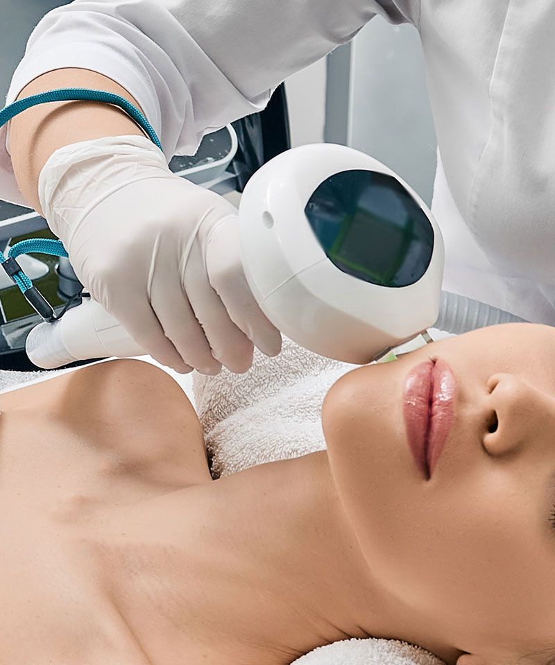 Woman receiving a skin treatment on her face. A device is being used on her chin.