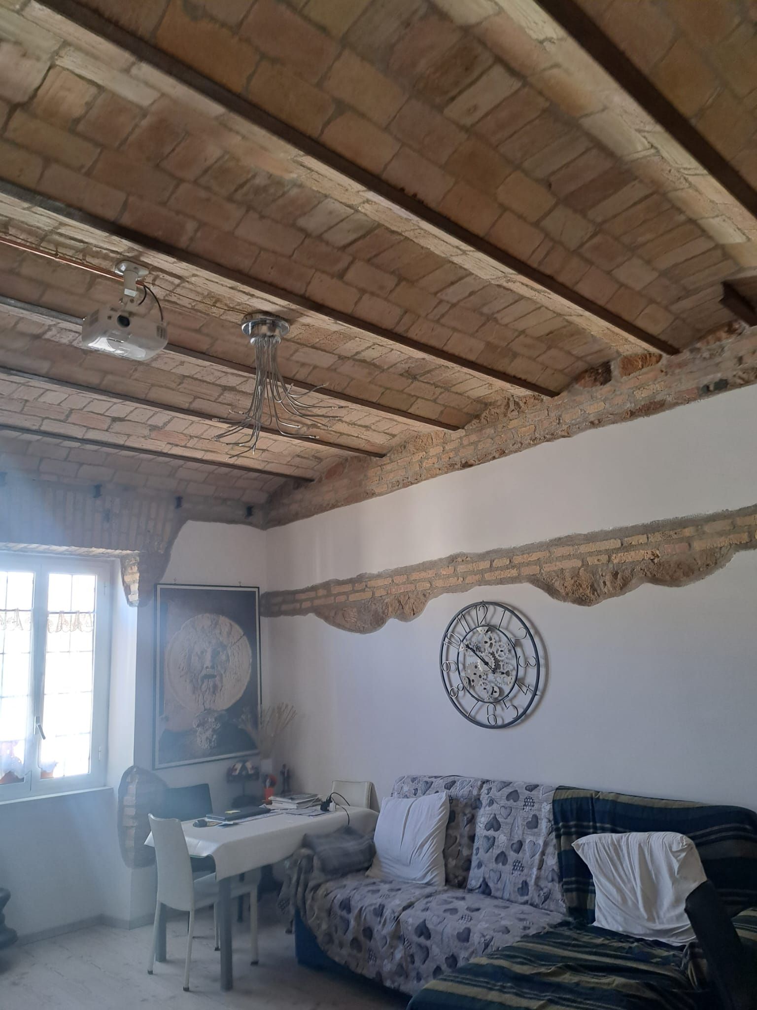 Un soggiorno con divano, tavolo, sedie e orologio a parete.