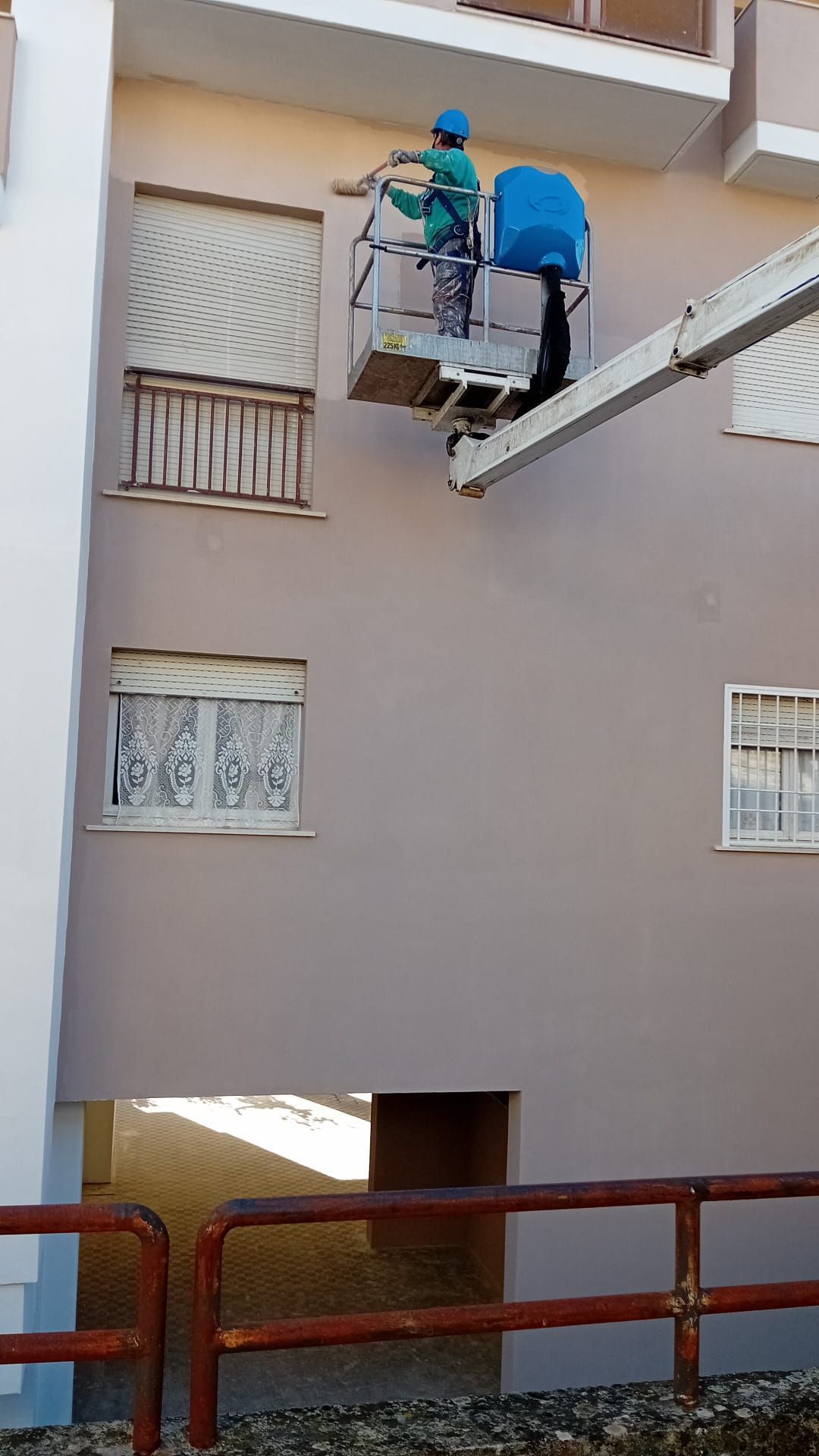 Un uomo sta dipingendo un edificio con una gru.