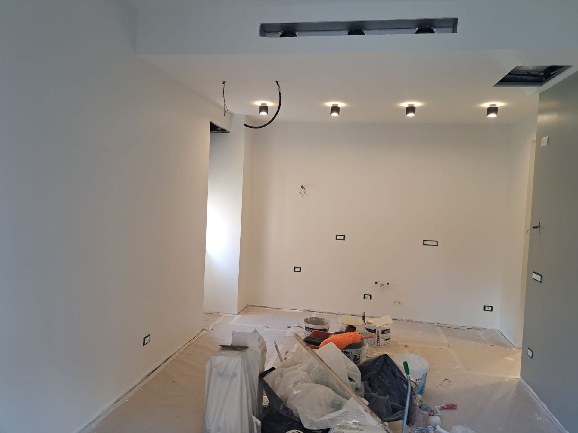 Una stanza con le pareti bianche e il soffitto in fase di verniciatura.