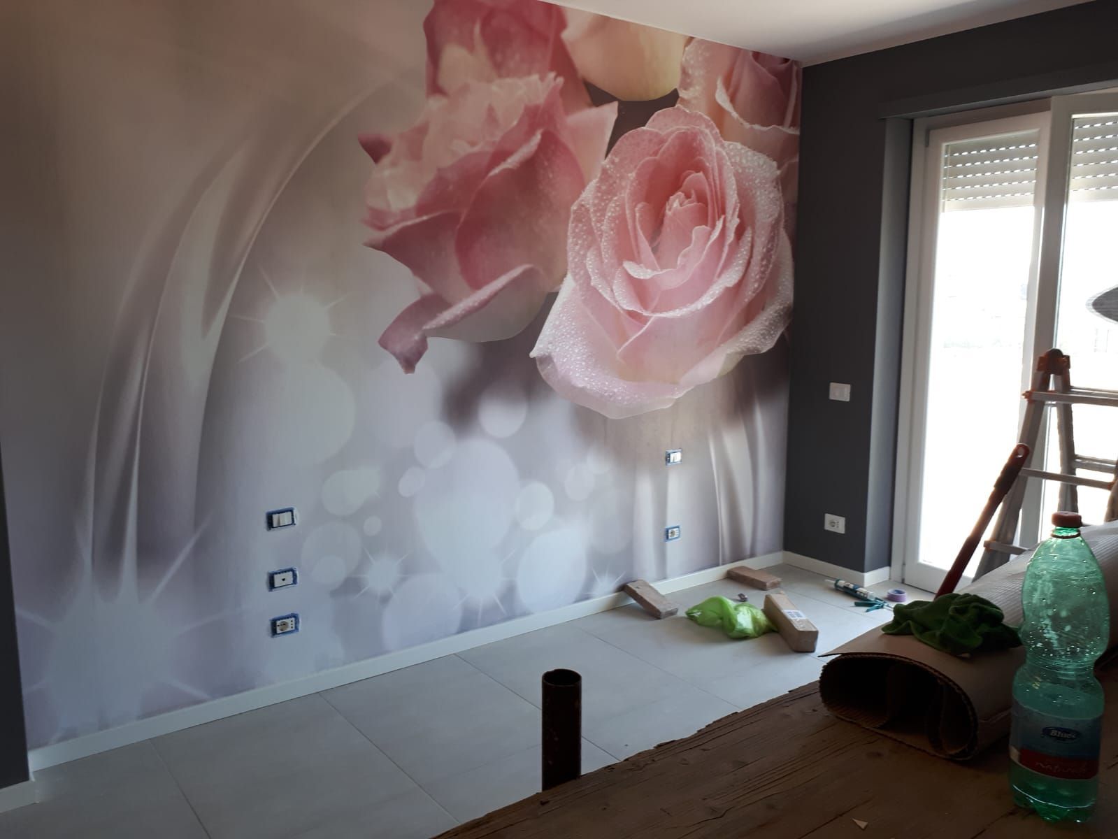 Una stanza con un murale di rose rosa sul muro