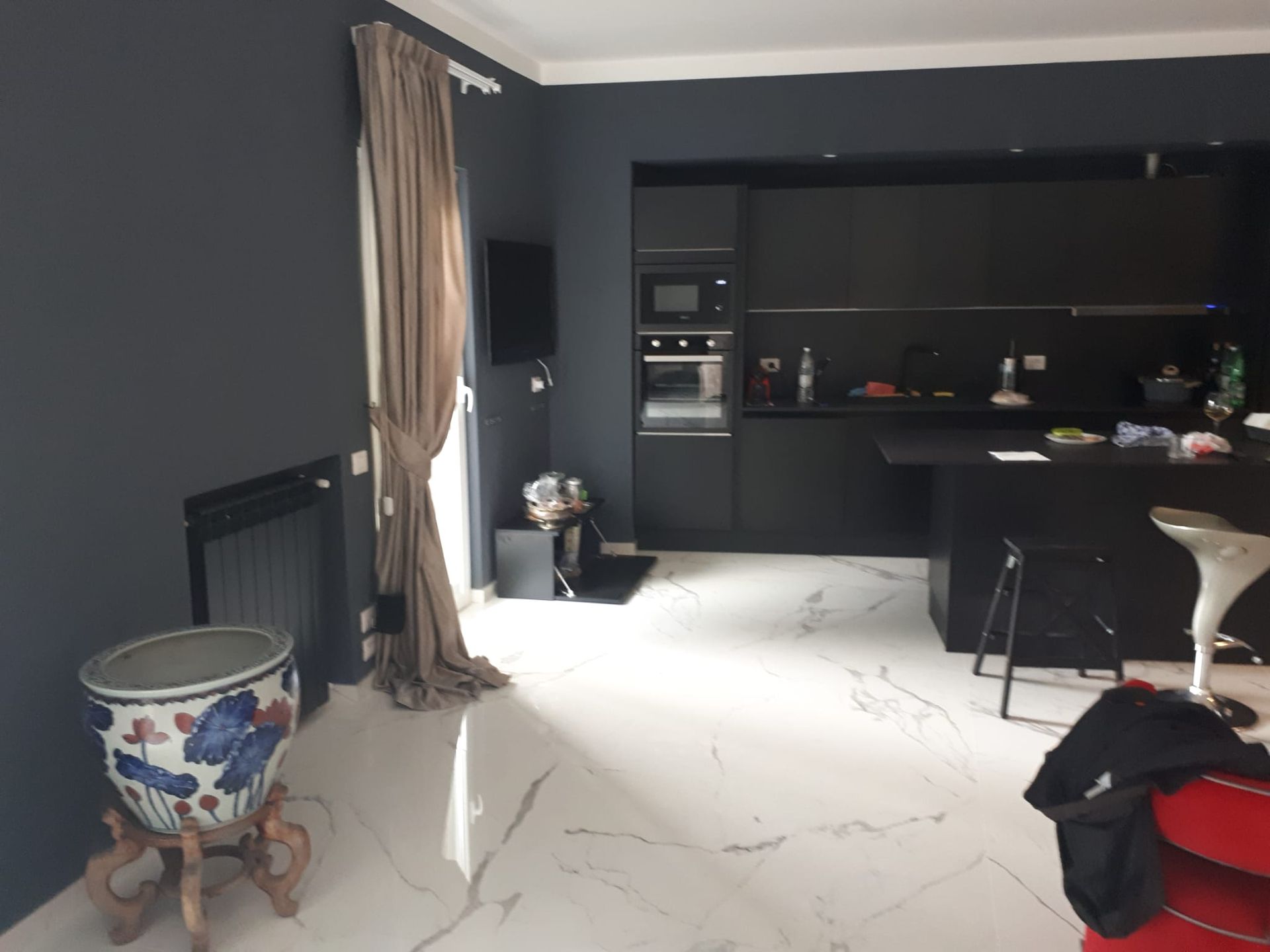 Un soggiorno con pareti nere e pavimenti in marmo bianco