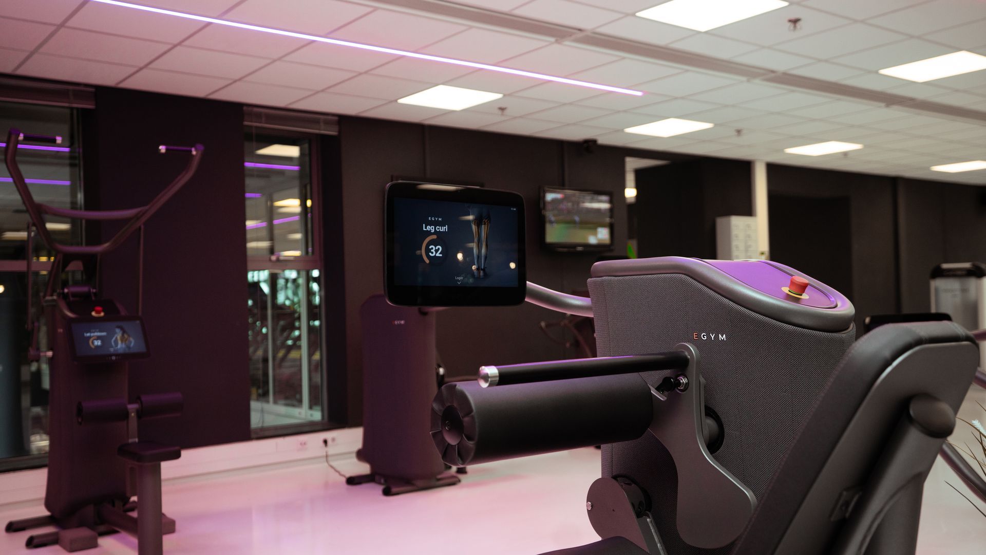 Een vrouw zit op een apparaat in een sportschool.