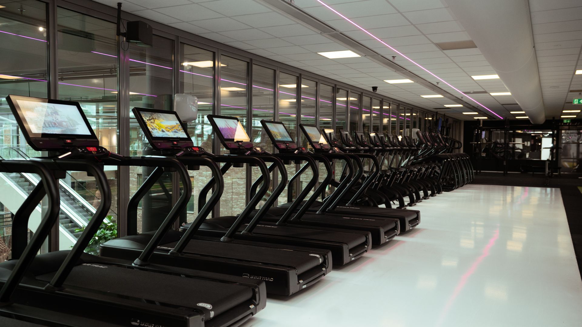 Een sportschool vol met fitnessapparatuur en televisies.