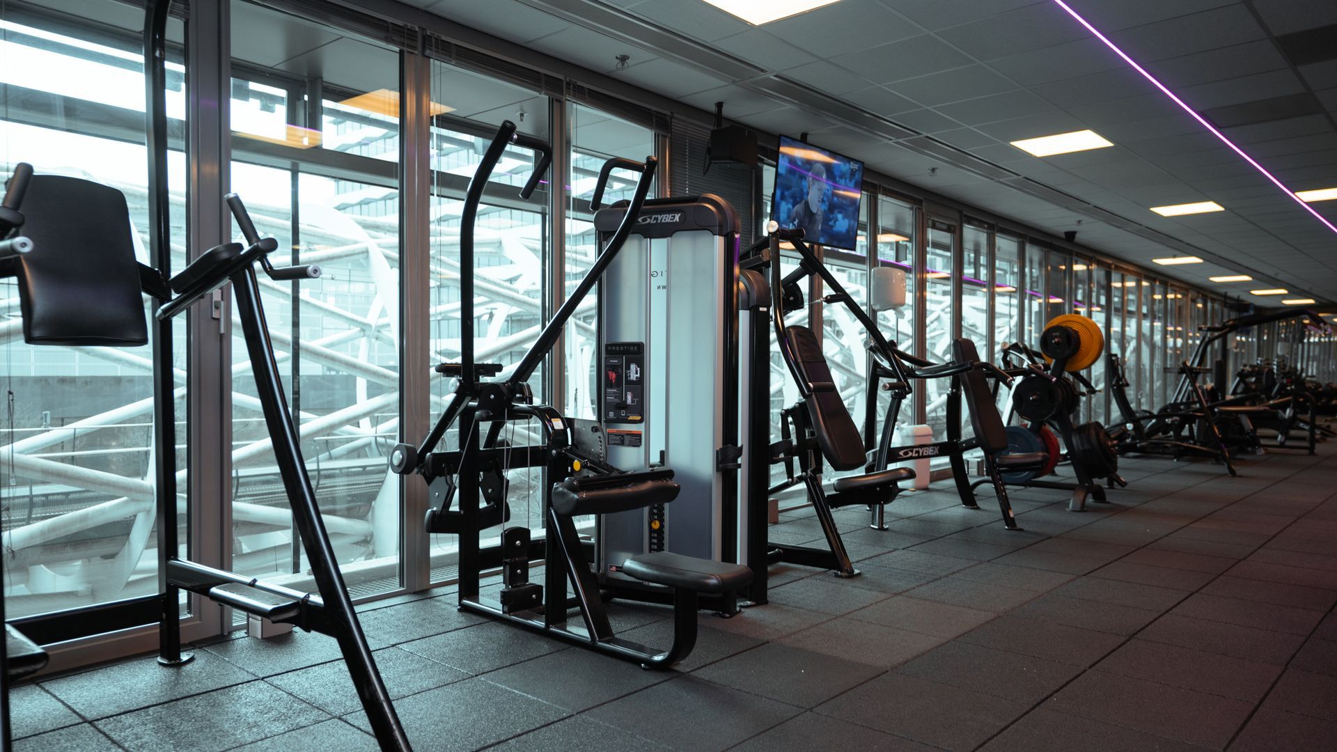 Een sportschool vol met fitnessapparatuur en televisies.