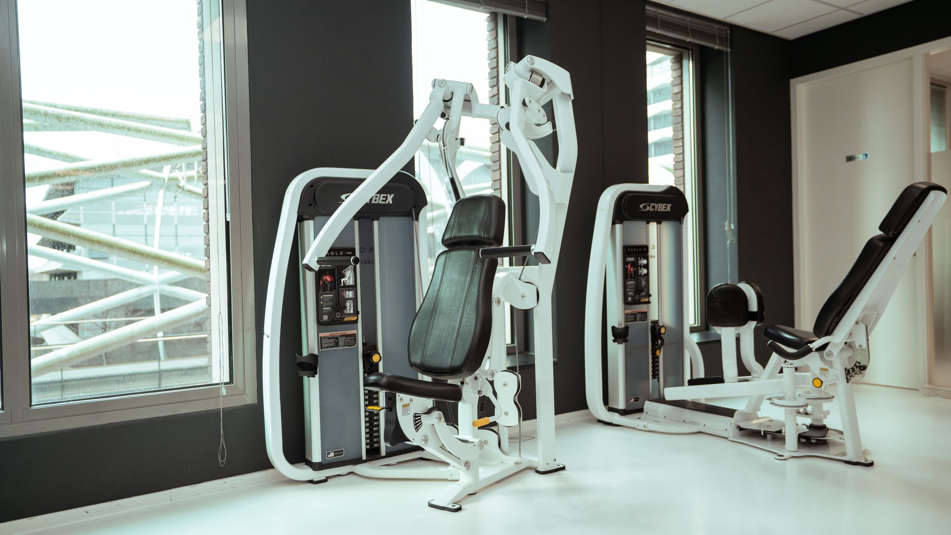 Een sportschool vol met fitnessapparatuur en televisies.