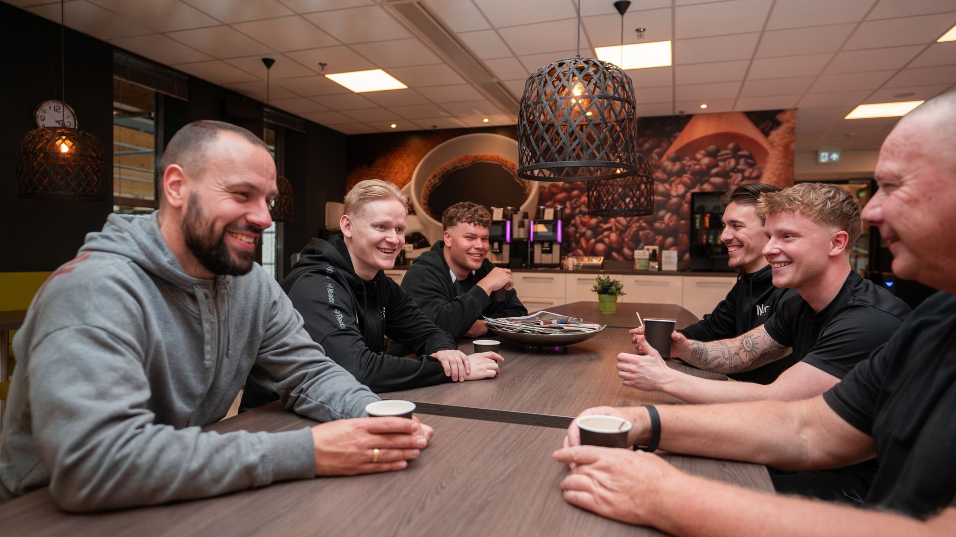 Een man helpt een vrouw met hurken met een halter in een sportschool.