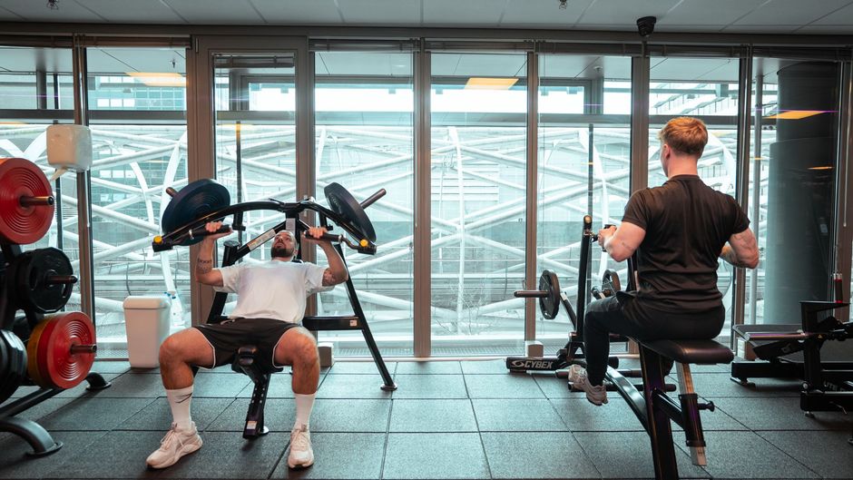 Een man en een vrouw fietsen op een hometrainer in een sportschool.
