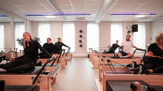 Een vrouw zit aan een bureau voor een computer en praat met een man.