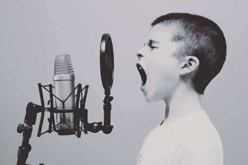 Garçon criant dans un microphone ; photo en noir et blanc.