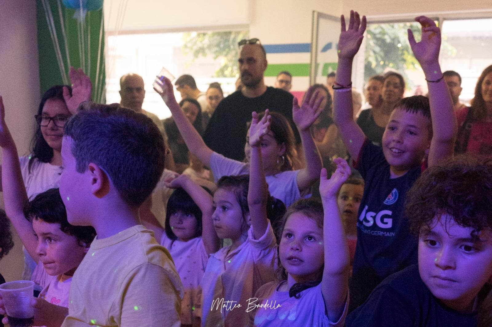 Un gruppo di bambini alza le mani in aria.