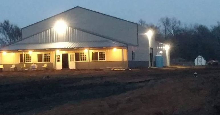 A large building is lit up at night in a field.