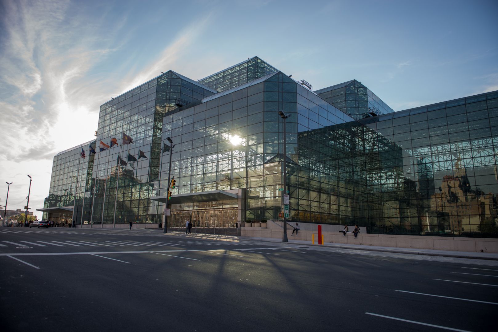 A large glass building is sitting on the corner of a city street.