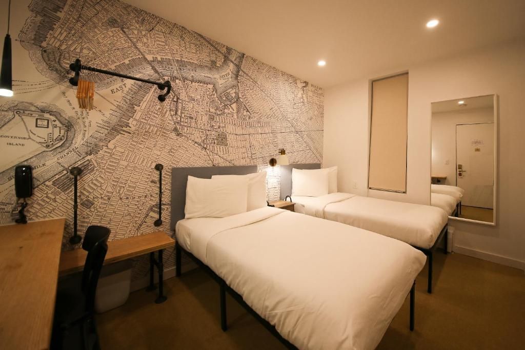 A hotel room with two beds , a desk and a mirror.