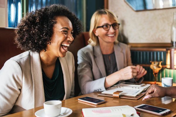 Two women are sitting at a table laughing.