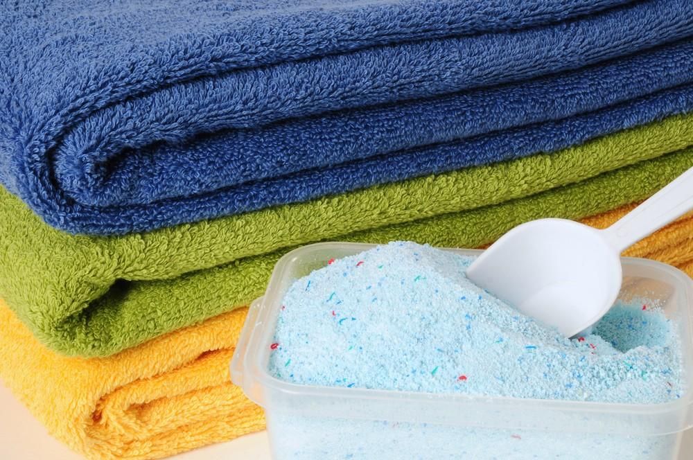 Stack of Colourful Towels with A Scoop of Blue Laundry Detergent — My Habitat Products in Mackay, QLD