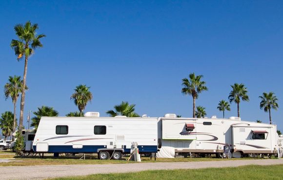 A couple of rvs are parked next to each other on a dirt road. A couple of rvs are parked next to each other on a dirt road.