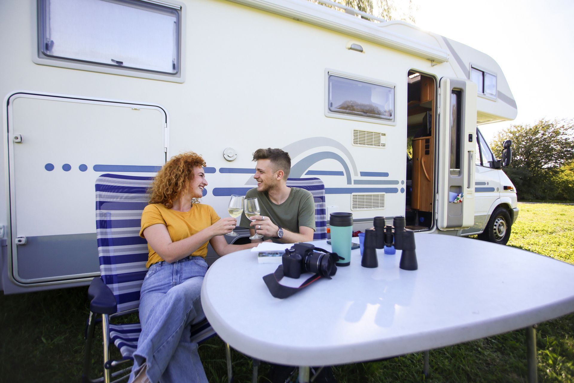 A man and a woman are sitting at a table in front of a rv.