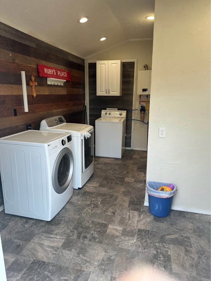 A laundry room with a washer and dryer and a trash can.