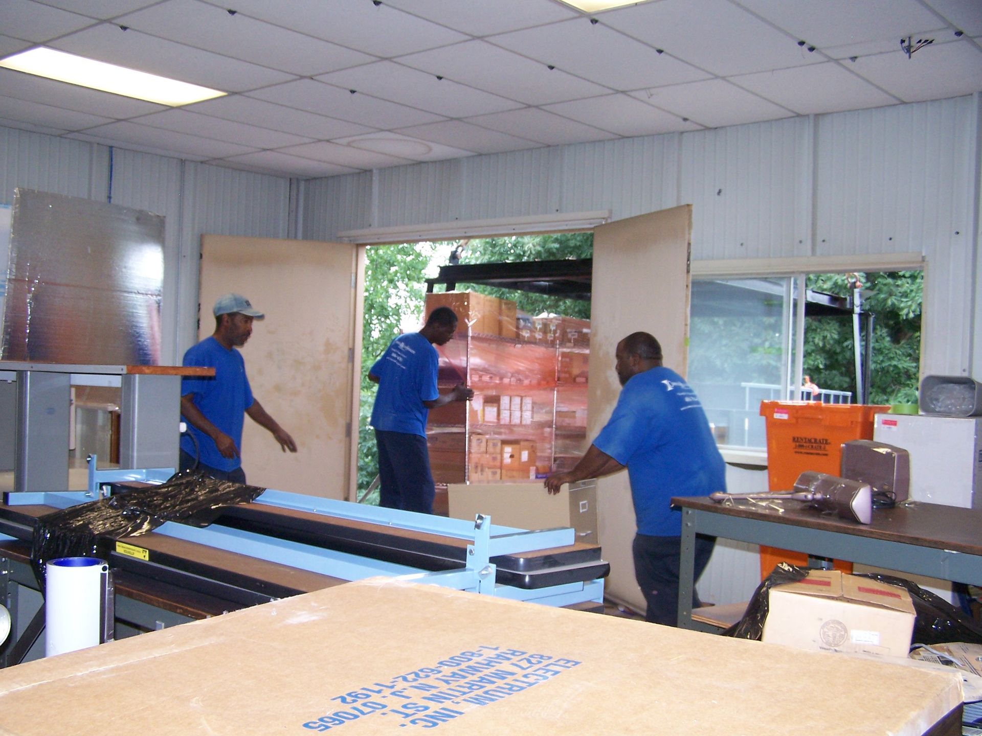 Three men in blue shirts are working in a room