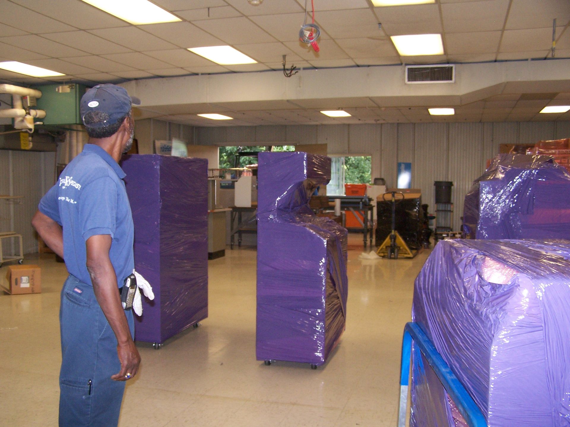 A man is standing in a room with purple boxes wrapped in plastic