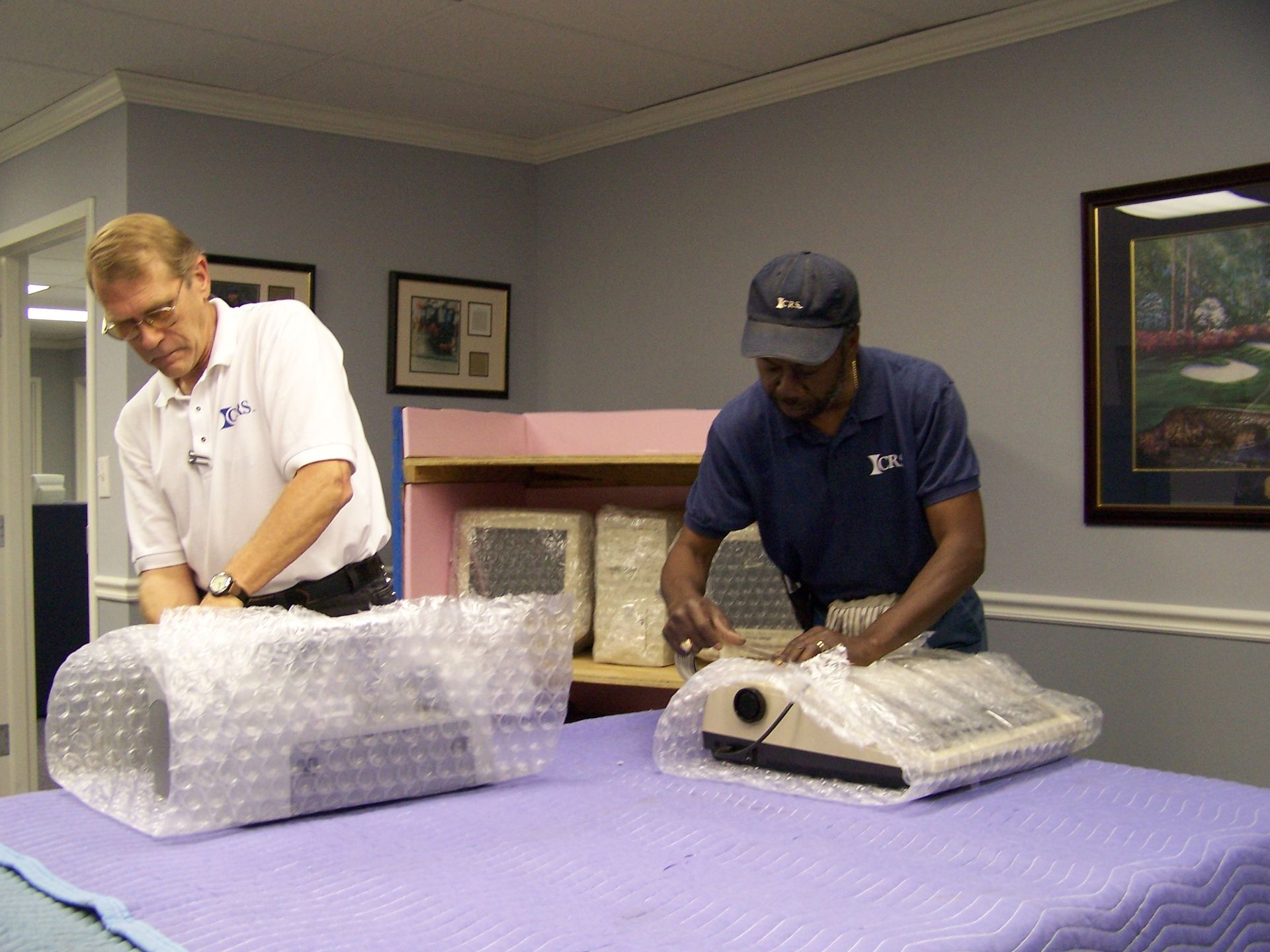 Two men are working on a table with bubble wrap on it