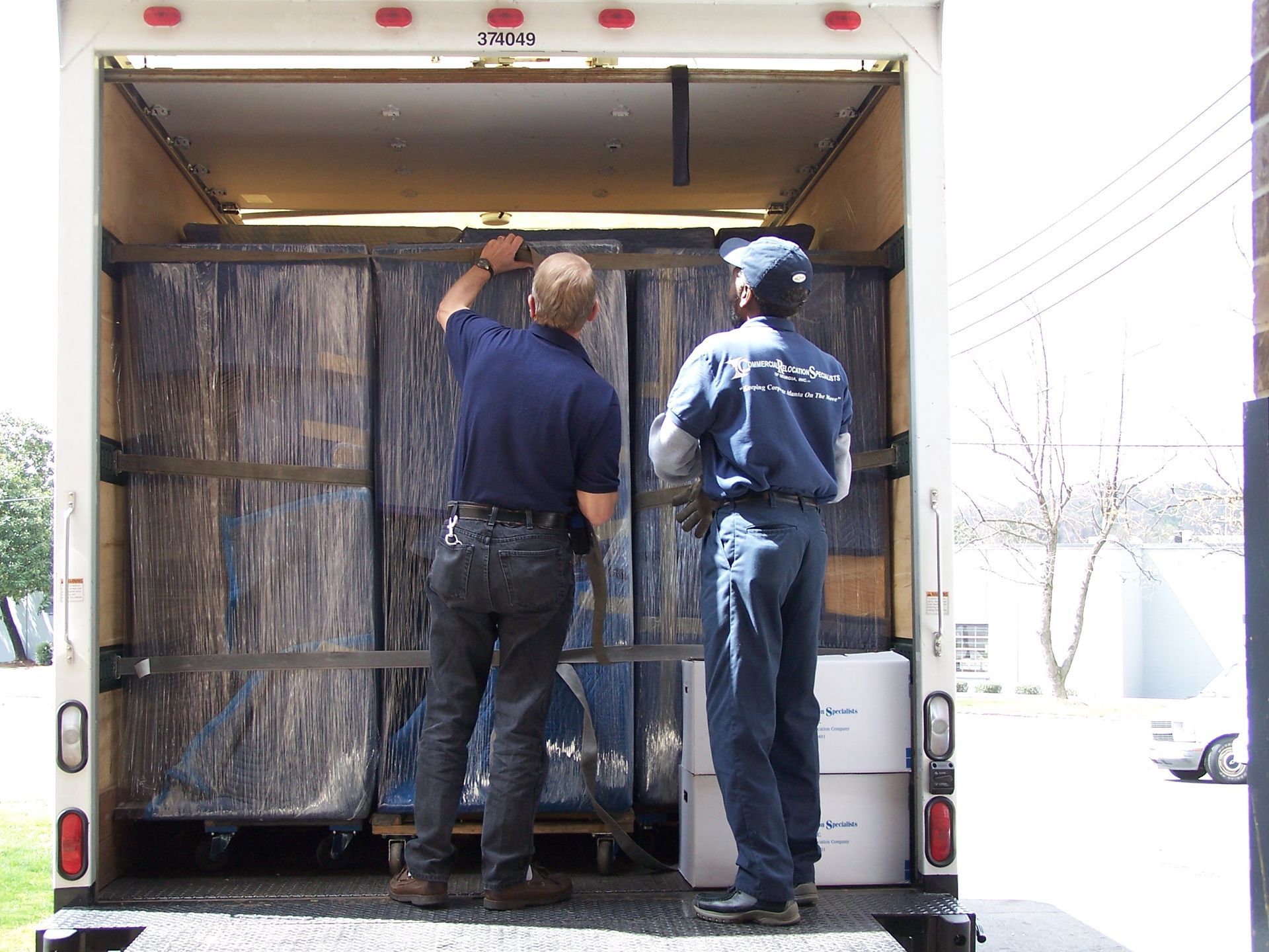 Two men are working on the back of a moving truck