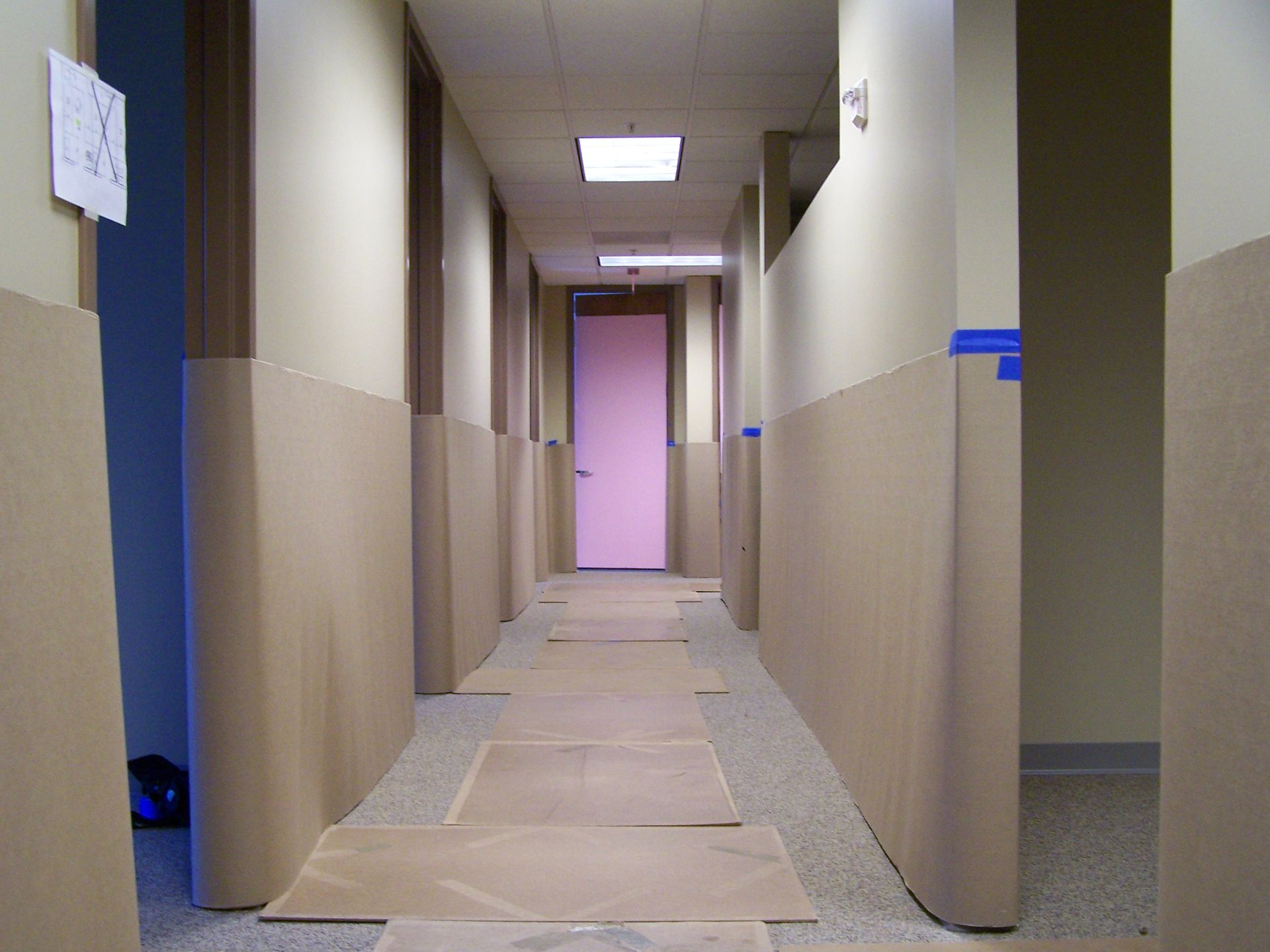 A long hallway with a pink door in the middle