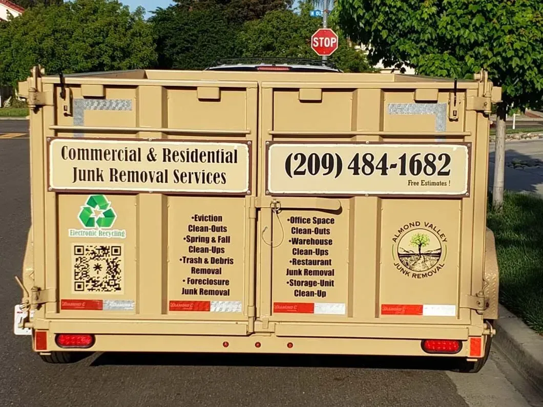 A dumpster is parked on the side of the road with a stop sign in the background.