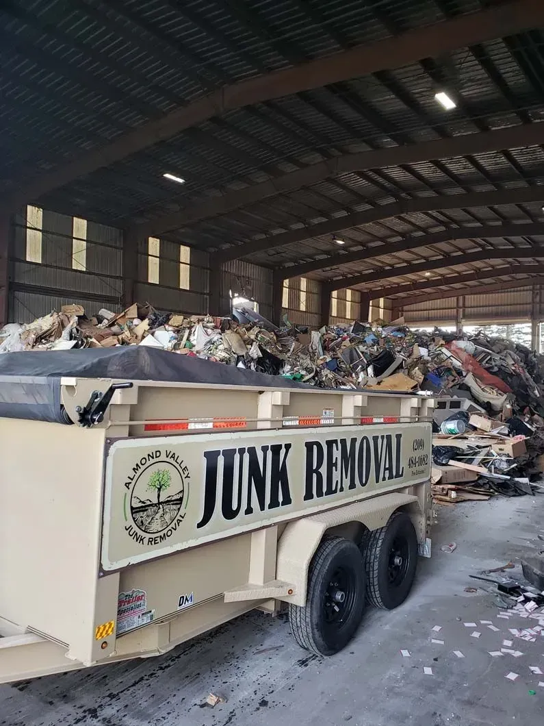 A junk removal trailer is parked in a warehouse filled with junk.