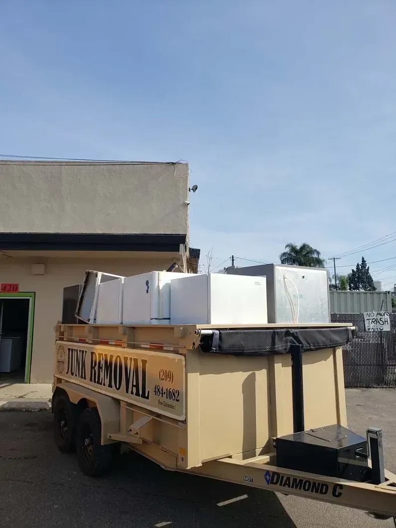 A trailer filled with boxes and appliances is parked in front of a building.