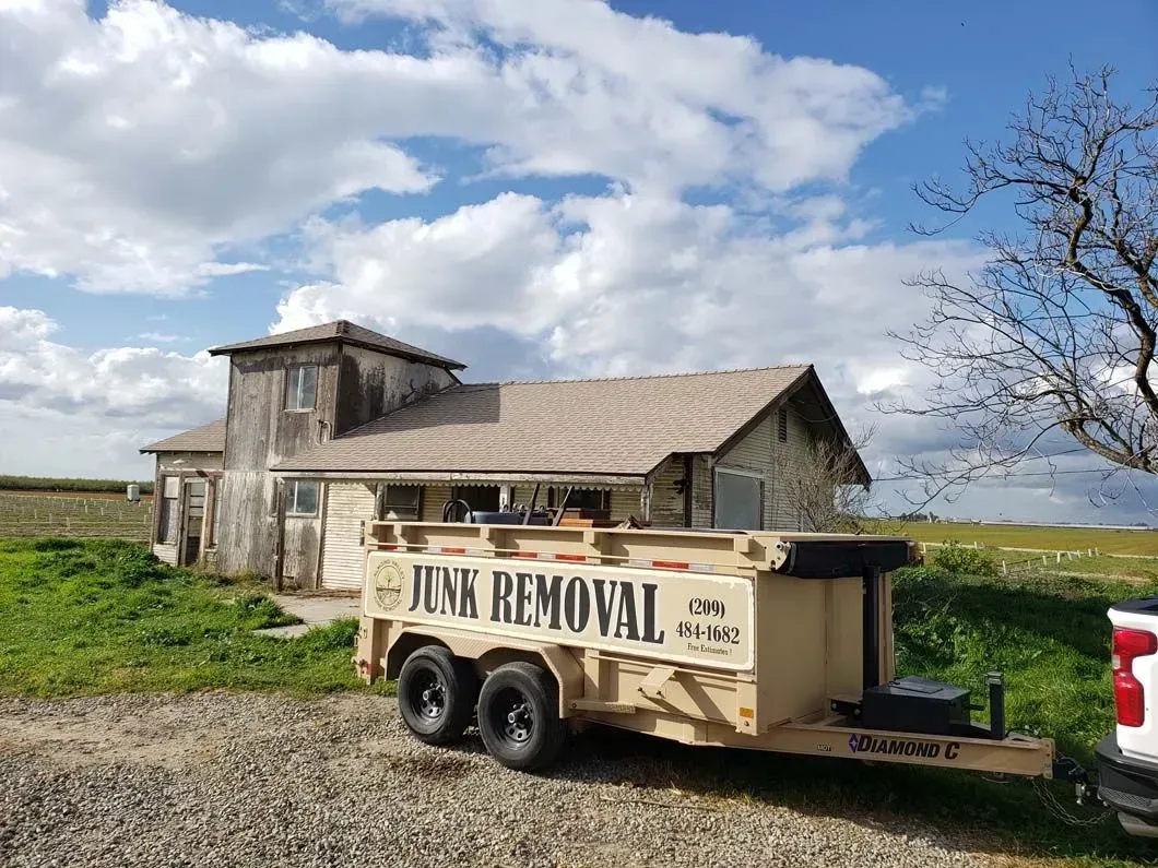 A junk removal trailer is parked in front of a house.