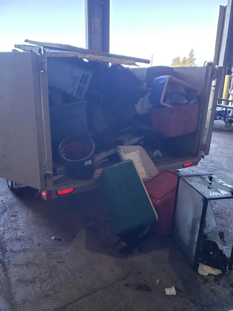 A trailer filled with lots of trash is parked in a parking lot.
