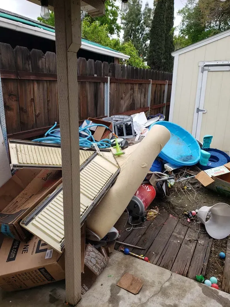 There is a lot of trash in the backyard of a house.