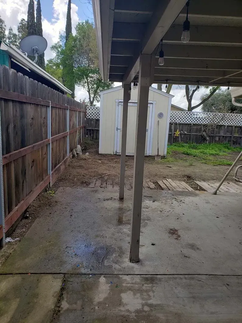 The backyard of a house with a wooden fence and a shed.