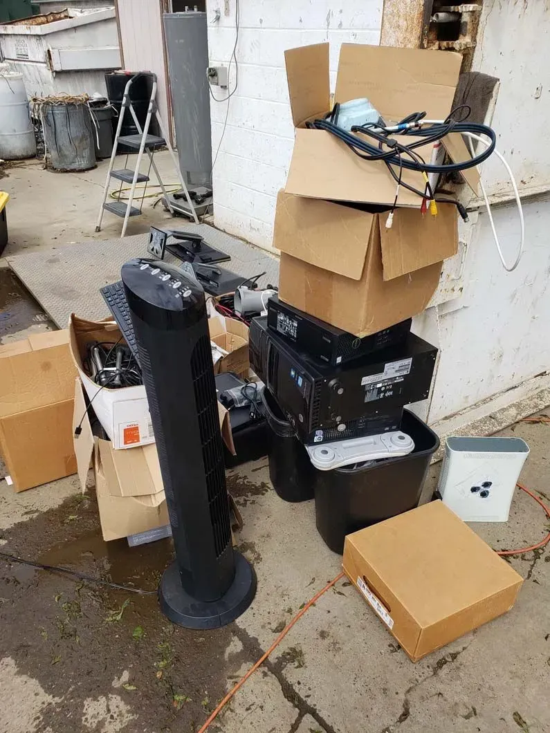 A stack of cardboard boxes sitting on the ground next to a speaker.