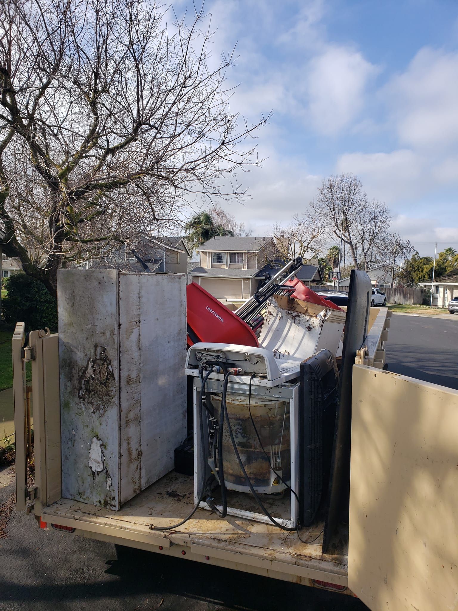 A dumpster filled with junk is parked on the side of the road.
