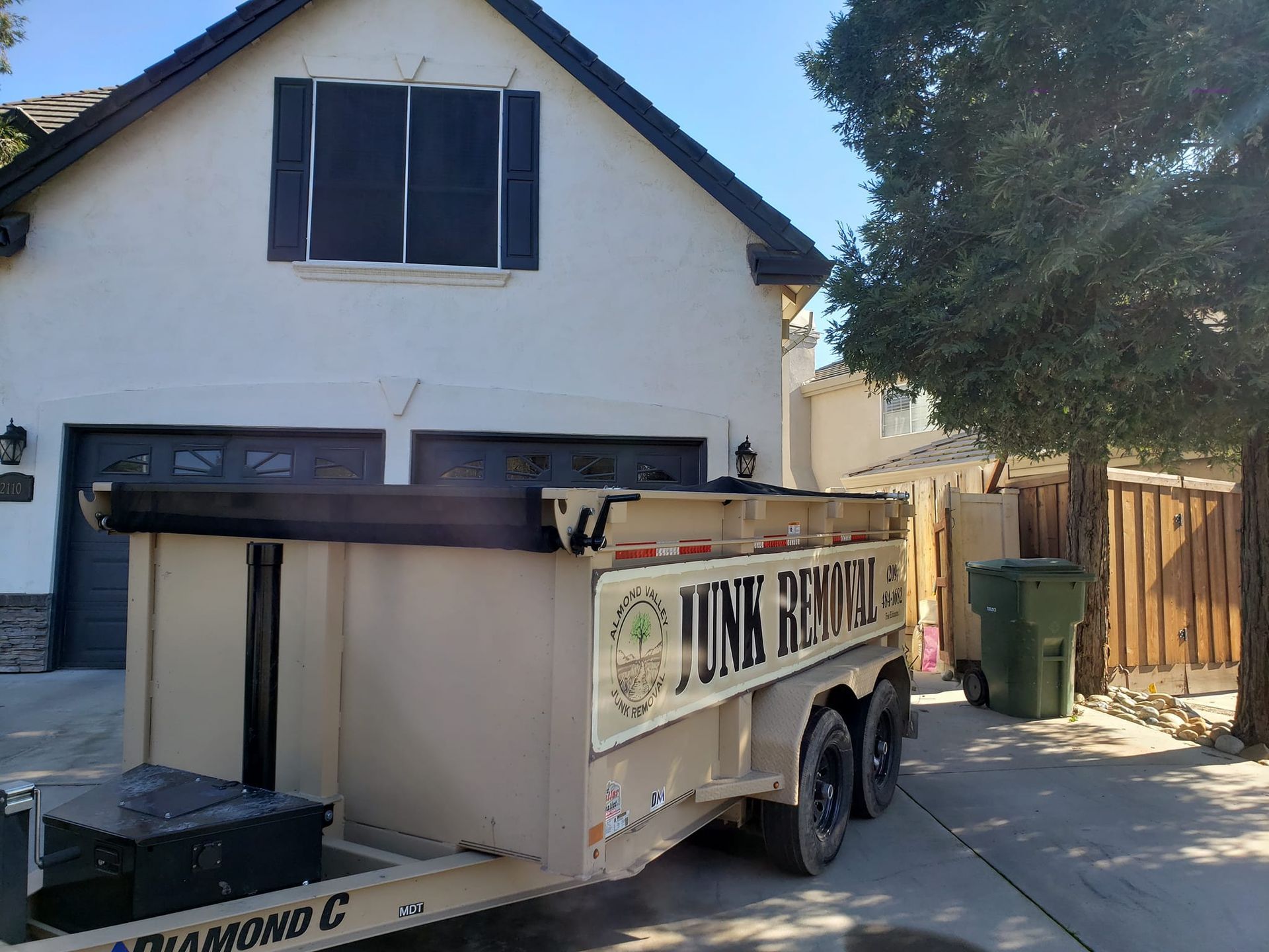 A junk removal trailer is parked in front of a house.