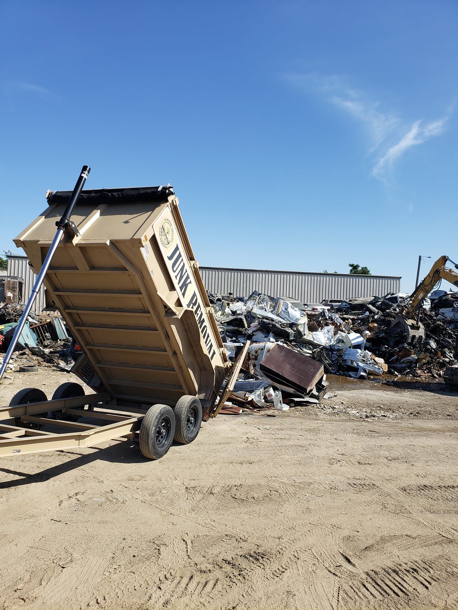 A dumpster is sitting in the middle of a pile of scrap metal.