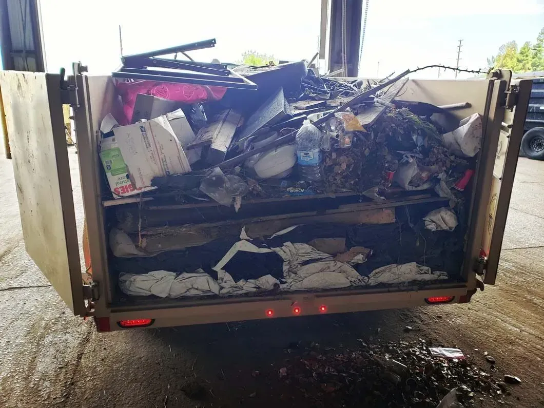 A dumpster filled with lots of trash is sitting in a parking lot.