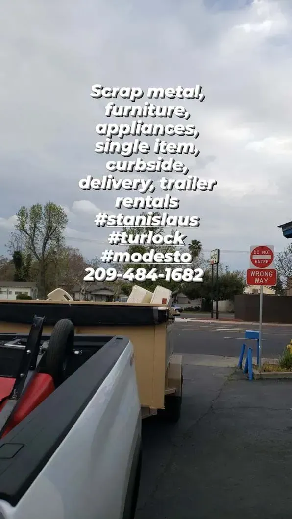 A white truck with a trailer attached to it is parked on the side of the road.