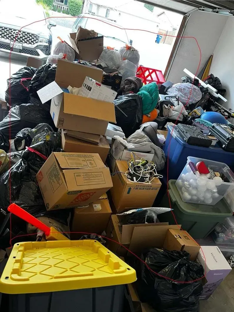 A pile of boxes and trash bags in a garage.