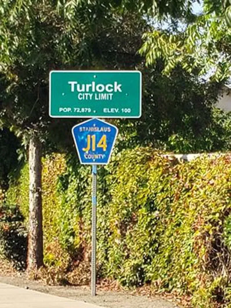 A green sign that says turlock city limit on it