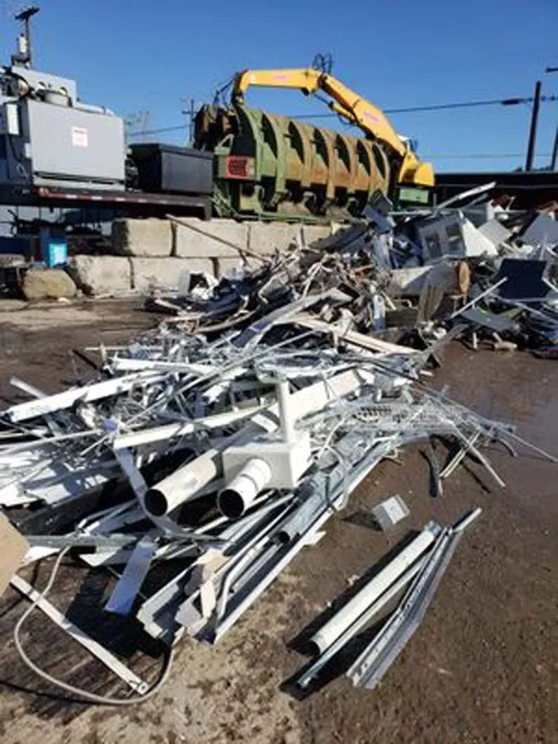 A pile of scrap metal with a yellow crane in the background